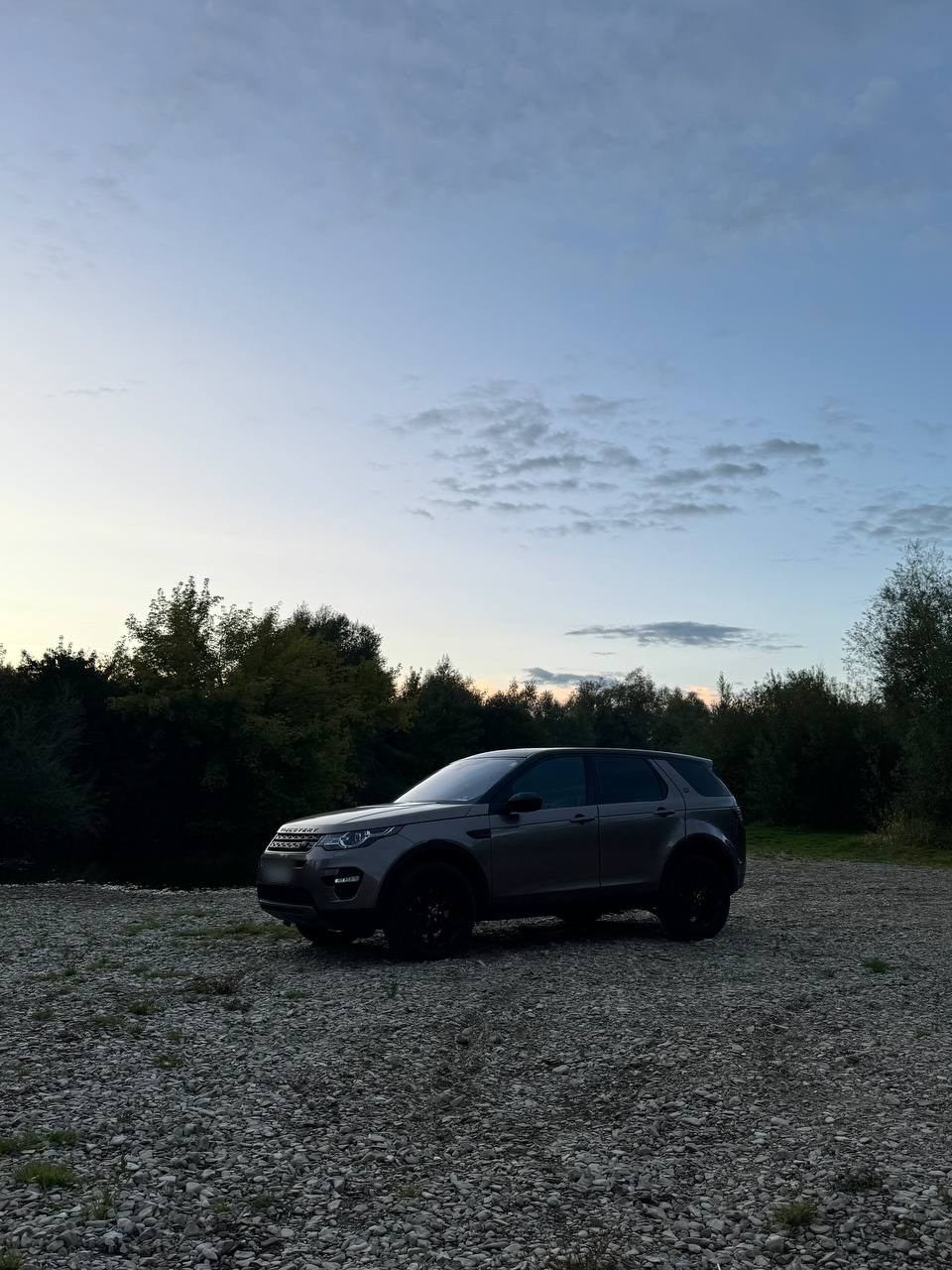 Коричневий Land Rover Discovery Sport учасника клубу на гальці під вечірнім небом