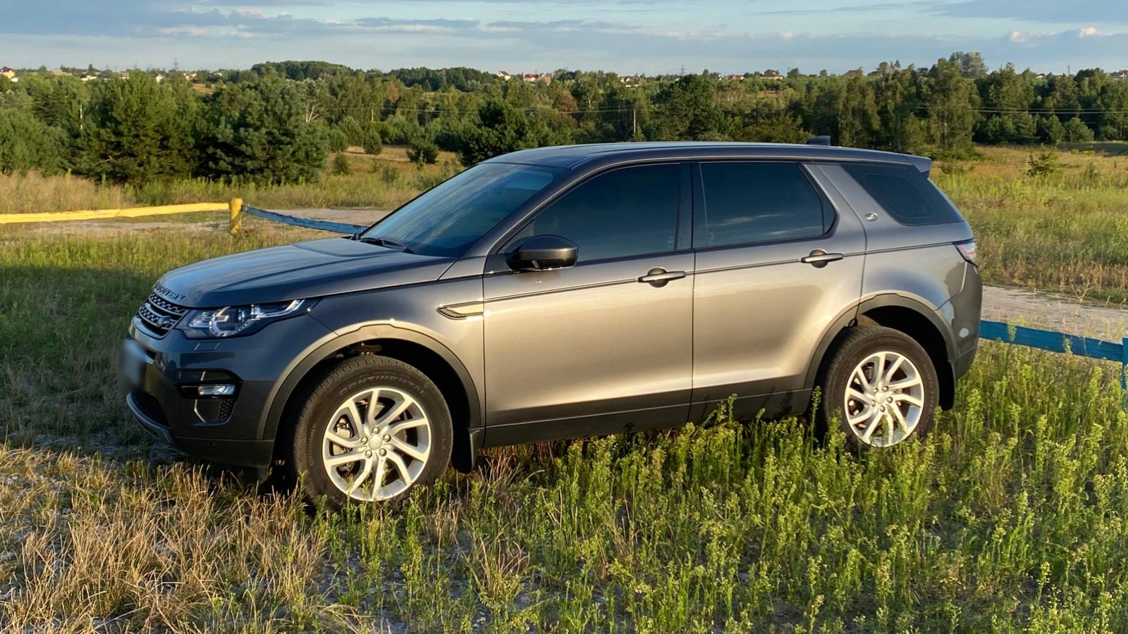 Сірий Land Rover Discovery Sport учасника клубу в полі біля лісу
