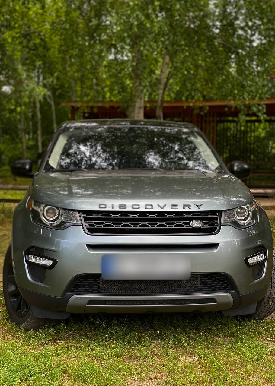 Сріблястий Land Rover Discovery Sport учасника клубу спереду: напис DISCOVERY, решітка й фари